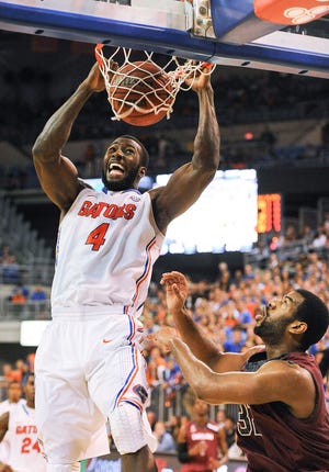 Florida center Patric Young (4) jams the ball through the basket for two points as South Carolina forward/center Desmond Ringer (32) is unable to stop the shot during the second half of an NCAA college basketball game Wednesday, Jan. 8, 2014 in Gainesville.