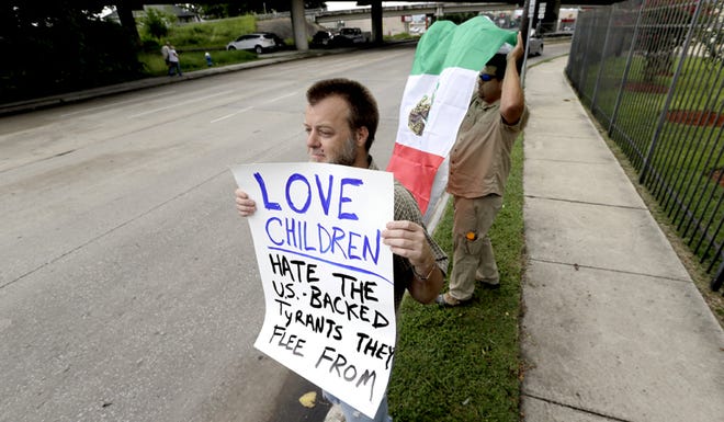 Bill Lambert holds a sign as he joins demonstrators outside the Mexican Consulate on Friday, July 18, 2014, in Houston. The sharp contrast in how Americans are reacting to the immigrant influx mirrors the divisiveness seen in Congress as the nation’s leaders attempt to find solutions to an issue that could worsen in the coming months.