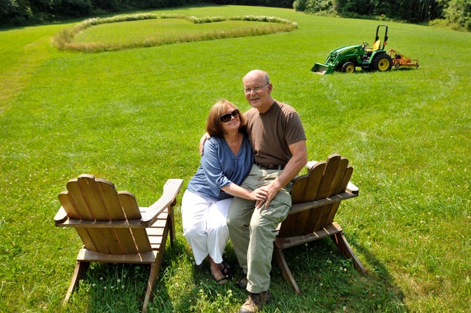 Patricia and Douglas Coldwell of Berlin, who have been married for 46 years, sit in a field on their property where Douglas has created a 120-foot-wide heart of daisies, wildflowers and tall grass. The heart, which can be seen from Route 62 in Berlin, has been a popular spot for couples to stop and take photos.