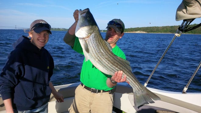 Mike Kelly and wife Missy proudly display the striper they recently caught in the waters of Mount Hope Bay. Mike took dad Fran out for a day of fishing on Father's Day.