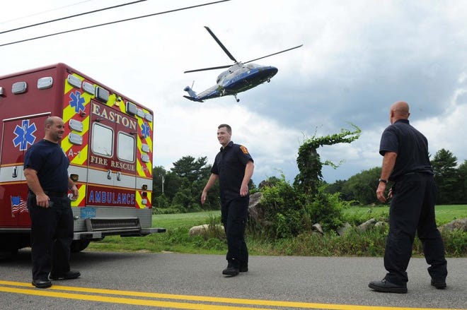 Easton rescue workers meet a Medflight helicopter after a pair of motorcycles crashed into the woods on Poquanticut Avenue in Easton on Saturday. One victim was airlifted to Boston with head and lower back injuries.