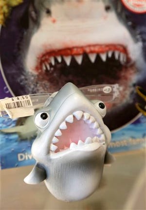 In this July 2, 2014 photo, an eye glass holder in the shape of a shark rests on a shelf in a souvenir shop in Chatham, Mass. With growing sightings of great white sharks off Cape Cod, local entrepreneurs are feeding the frenzy with their shark-themed memorabilia and apparel. (AP Photo/Steven Senne)