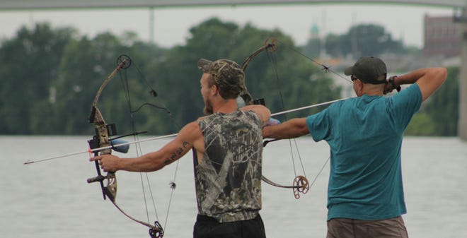 Bowfishermen on the Illinois River draw back their arrows in hopes of pulling in an Asian Carp during the first annual Flying Fish Bowfishing Tournament on July 12.