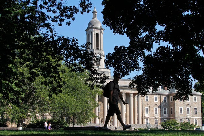 In this July 12, 2012 file photo, a student walks past Old Main on the campus of Penn State University in State College, Pa. Students who earned diplomas in the aftermath of the deepest U.S. recession since the 1930s are experiencing an earnings hangover that could last a lifetime, even as the labor market heals.