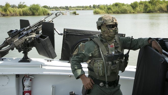 A masked Department of Public Safety trooper prepares to patrol the Rio Grande between McAllen and Reynosa, Tamaulipas, Mexico, on a boat with M240 machine guns on Wednesday. The boat patrols are part of the law enforcement surge to attempt to secure the border.