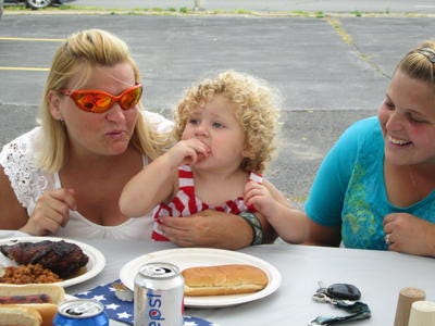 ALISSA SCOTT / Observer-Dispatch
Alayna Crever, 1, eats a hot dog at the Rome American Legion's annual chicken barbecue to celebrate Honor America Days. With her is her mother, Chanda Crever, right, and her grandmother Marlene Eaton.