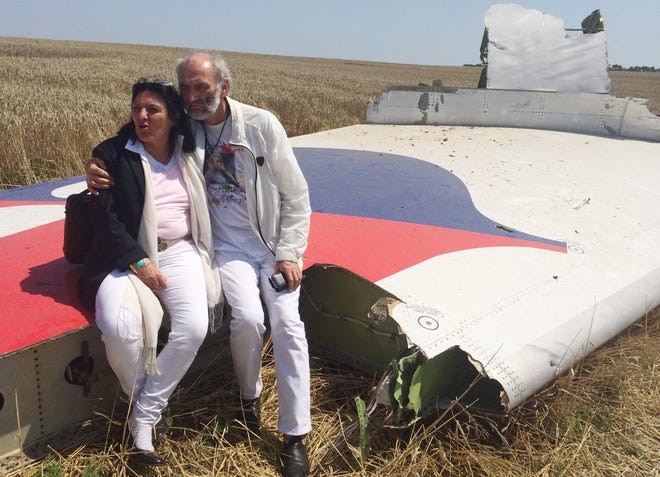 Jerzy Dyczynski and Angela Rudhart-Dyczynski of Perth, Australia, whose daughter, Fatima, 25, was a passenger on Malaysia Airlines Flight MH17, sit on part of the wreckage of the crashed aircraft Saturday in Hrabove, Ukraine.