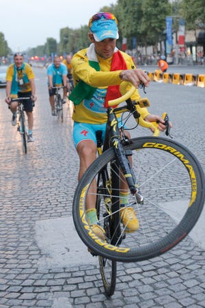 2014 Tour de France cycling race winner Italy's Vincenzo Nibali pulls a wheelie during the team parade of the Tour de France cycling race in Paris, France, Sunday, July 27, 2014.