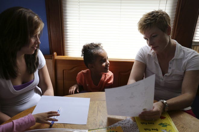 During a monthly visit, SPARK parent partner Holly Lawrence, right, assists Shawana Barido in preparing her 4-year-old daughter, Ariana Davis, for kindergarten. SPARK provides lesson plans, books, activities and supplies at no charge.