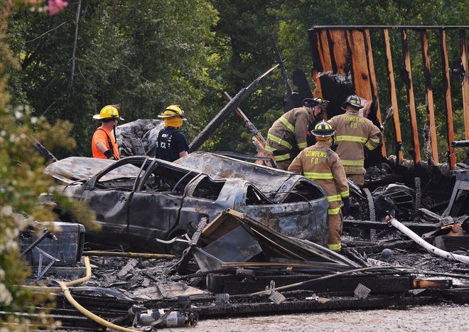 Firefighters with Macedonia, Cowpens, Chesnee Community, and Cherokee Creek fire departments, work to contain a fire that destroyed a building containing two vehicles near a home on Bobcat Trail in Cowpens, Monday afternoon, 7-28-2014.