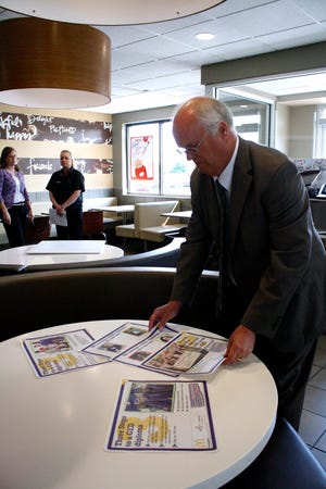 John Strandin, public relations manager at the Northern Illinois Workforce Alliance, displays tray liners Tuesday, July 29, 2014, that will be used at local McDonald’s restaurants over the next month to spread the word about GED attainment.