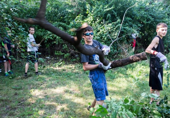 Drew Wheatley, 13, of Goshen, Ind., tosses a part of a tree into a pile Tuesday, July 29, 2014, in the 400 block of Heath Street in Rockford. Wheatley and 28 others from River Oaks Community Church came to participate in Project Facelift.
