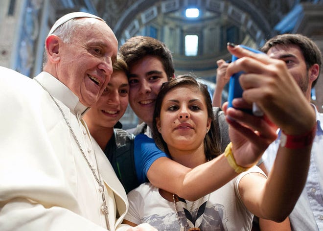 One example of an usie: Pope Francis has his picture taken with a group of Italian youths inside St. Peter's Basilica in August.