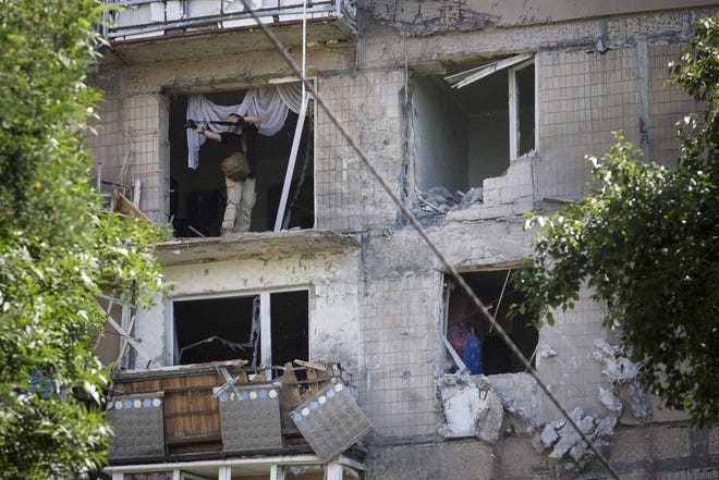 A man leans out to take a photo from a damaged residential apartment house after shelling in Donetsk, eastern Ukraine, Tuesday, July 29, 2014. Local residents said it was a shelling from direction of Ukrainian army's positions. (AP Photo/Dmitry Lovetsky)