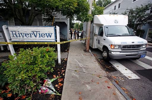 Flowers are seen near a crime scene at an apartment complex where five members of a family, including three children, were found dead Sunday, July 27, 2014, in Saco, Maine. The bodies of a father, mother and children were found inside the apartment, state police spokesman Steve McCausland said.