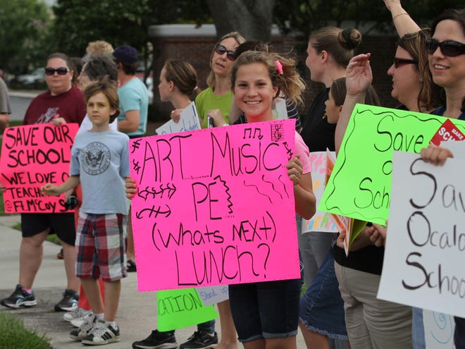 In this June 11, 2013 file photo, people protest layoffs at the Marion County School Board in Ocala. The board is looking to once again hire music and art teachers.