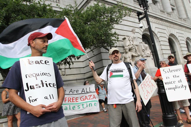 Wallace Sillanpoa, center, waves the Palestinian flag during a vigil Friday in Kennedy Plaza.