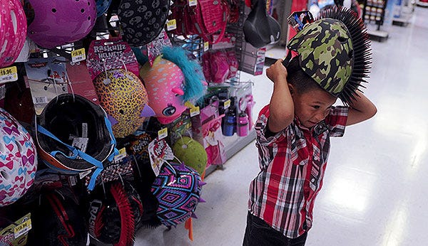 Paul Rether, 5, tries on a bike helmet during a shopping spree Thursday at Walmart.