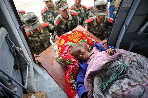 In this photo released by China's Xinhua News Agency, rescuers convey an injured person in the quake-hit Longtoushan Town of Ludian County in Zhaotong city, southwest China's Yunnan Province, Monday, Aug. 4, 2014. Rescuers dug through shattered homes Monday looking for survivors of a strong earthquake in southern province as the death toll rose to hundreds of people, with more than a thousand injured.(AP Photo/Xinhua, Xue Yubin)