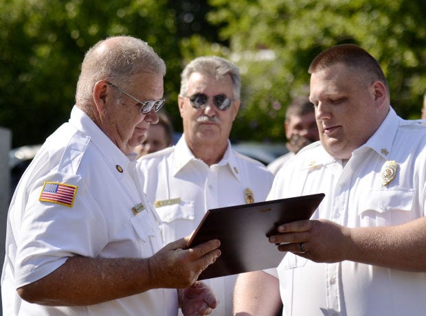 The Patterson Heights Volunteer Fire Department's Jason Medlin, right, gives a service award to volunteer firefighter Dennis Portman for his 50 years of service as fire department president as Larry Barkley watches on Sunday, August 3, 2014, outside the Patterson Heights Volunteer Fire Department.