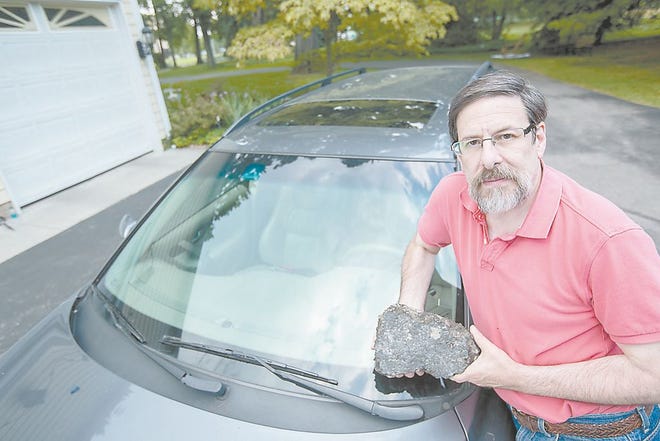 Bob Lubell holds the 8-pound piece of asphalt that was dropped on his car from above a freeway interchange in Toledo in 2003. It shattered his windshield and injured his hand.
