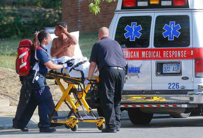 A man who was stabbing in the chest near the intersection of SE 10th and Wear, late Monday afternoon, points towards a family member while being wheeled to an ambulance by paramedics.