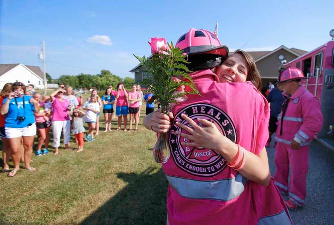 Morgan Kottman, a 14-year-old with a cancerous tumor on her brain stem, receives a hug Monday from firefighter and Pink Heals volunteer Luke Hays, of Kansas City, Kan., while the Pink Heals tour does home visits to people with cancer in Topeka.