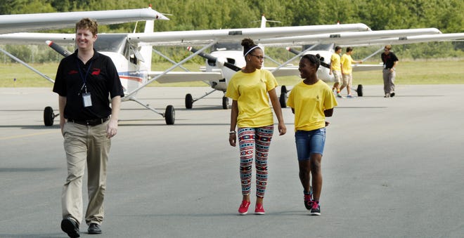 Flight instructor Greg Bruce and students Zuleica Fernandes, left, and Emily Miranda cross the tarmac at New Bedford Municipal Airport after a flight from Plymouth on Monday.