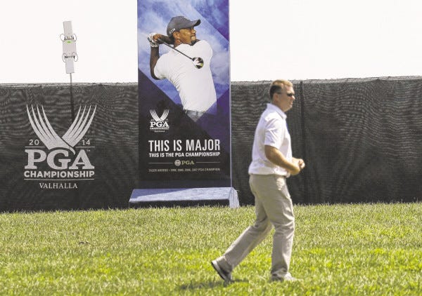 Jeff Roberson/The Associated Press
A man walks past a photo of Tiger Woods at Valhalla Golf Club on Monday in Louisville, Ky. Whether Woods will play in the PGA, which is set to begin on Thursday, is unclear after he suffered a setback Sunday when he was stricken with back pain and withdrew after eight holes from the Bridgestone Invitational.