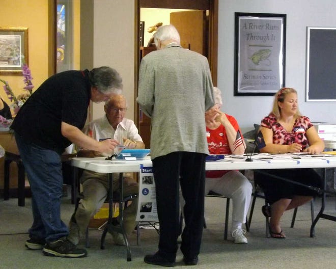 Randy Schmidt, far left, supervising judge, works on an iPad on Tuesday with Jean Gunther, second from left, at First United Methodist Church, 600 S.W. Topeka Blvd. This was the first election for using electronic poll book.