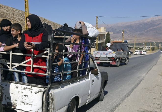 Thousands of Lebanese civilians and Syrian refugees pack cars and pickup trucks, fleeing an eastern border town that was overrun by militants from neighboring Syria.