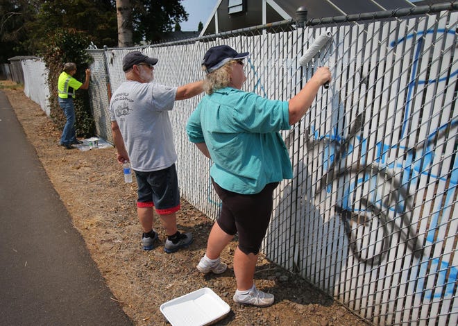 Springfield City Councilor Sheri Moore and her husband, Neal Moore, join other painting volunteers to cover graffiti along Â­the Eugene Water & Electric Board Bike Path in Springfield on Tuesday. “There are kinds of graffiti that are artistic and sought after, but there is also graffiti that looks territorial and has a sense of criminal activity,” Mayor Christine Lundberg said. (Brian Davies/The Register-Guard)