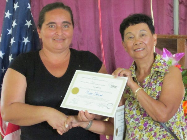 Mari-Lou Wong-Chong (right) hands Mariana Moldonado a certificate saying Moldonado has completed a course taught by the Christian group the Wong-Chongs were traveling with in Honduras. Photo by George Wong-Chong