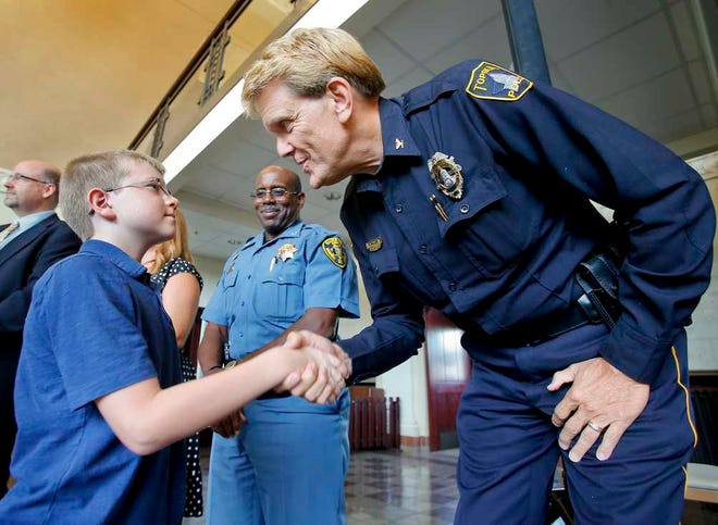 Johnathan Kelly, 10, gets congratulated by former Topeka Police Chief Ron Miller after receiving the Champion of Character Award Wednesday afternoon at the Great Overland Station. Kelly received the award for his swift and calm actions to alert family members and guide paramedics to the location where his mother slipped and fell, fracturing her skull, on May 31.