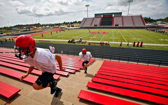MUSTANG HIGH SCHOOL FOOTBALL STADIUM / RENOVATE / RENOVATION: Players runs steps on the old grandstands as the new home grandstands and press box get the final touches of work during the Mustang Broncos' team football practice on Tuesday, Sept. 7, 2010, in Mustang, Okla. The new addition to the Broncos' stadium will be completed for the team's first home game this Saturday. Photo by Chris Landsberger, The Oklahoman ORG XMIT: KOD