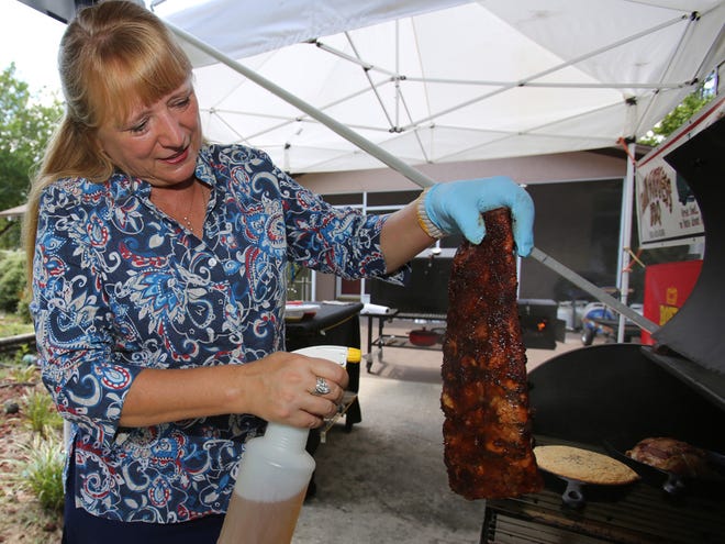 Lori Frazee sprays Baby Backs with a solution of white grape, peach and apple juice mix as she barbecues at her home in Rainbow Lakes Estates on Tuesday.