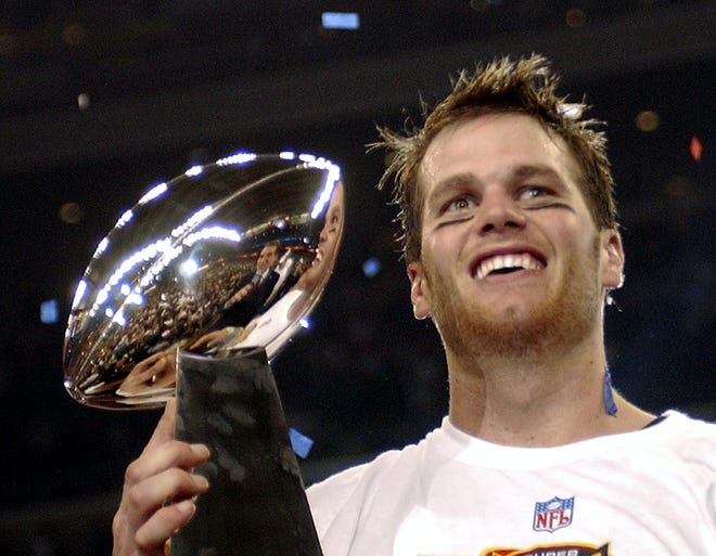 In this Feb. 1, 2004 file photo, New England Patriots quarterback Tom Brady holds the Vince Lombardi Trophy after the Patriots beat the Carolina Panthers 32-29 in Super Bowl XXXVIII in Houston. The salary cap, extra playoff games and a league bent on parity have made the NFL one of the planet’s most competitive leagues, where champions fall quickly and teams regularly make one-season turnarounds.