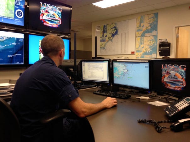 Coast Guard Petty Officer 1st Class Corley Myres looks at a bank of monitors in the Sector N.C. Command Center on Friday, Aug. 8, 2014.