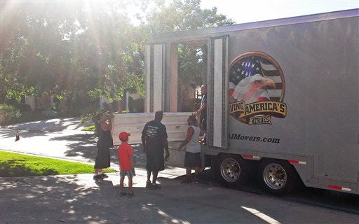 In this July 3, 2014 photo provided by Cynthia Kent, Jack Kent, age 8, watches movers load his family belongings for a move from Las Vegas to Montgomery, Ala., for a new Air Force assignment. Jack's parents rent out their home in Florida as the family moves around the nation, and they have become experienced at finding good tenants and maintaining their house from a distance. (AP Photo/Cynthia Kent)