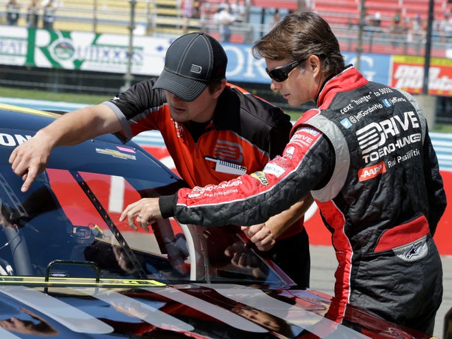 Jeff Gordon, right, examines a mark on his windshield before Saturday's qualifying session for Sunday's Sprint Cup race at Watkins Glen International in Watkins Glen N.Y.
