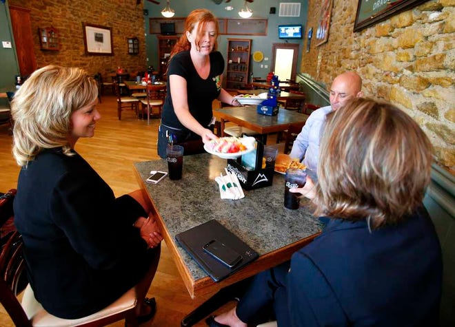 Katie Turner, a waitress at The Celtic Fox, delivers food to a table of customers Thursday afternoon.