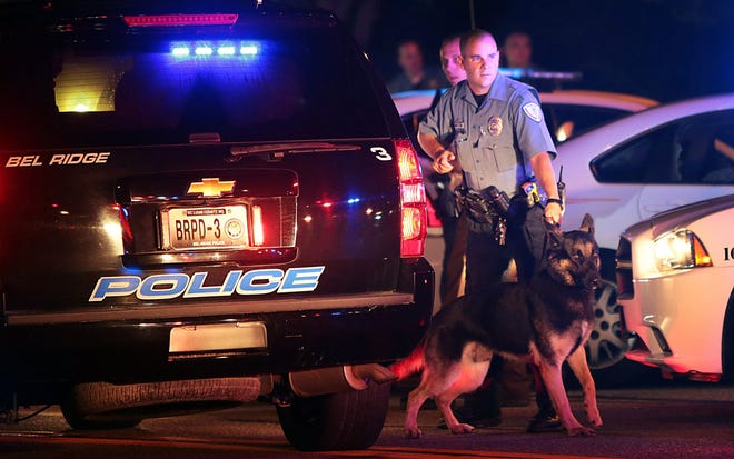 Police officers patrol the area Sunday in Ferguson, Mo. A few thousand people crammed a suburban St. Louis street Sunday night at a vigil for unarmed 18-year-old Michael Brown shot and killed by a police officer, while afterward several car windows were smashed and stores were looted as people carried away armloads of goods as witnessed by an an Associated Press reporter.