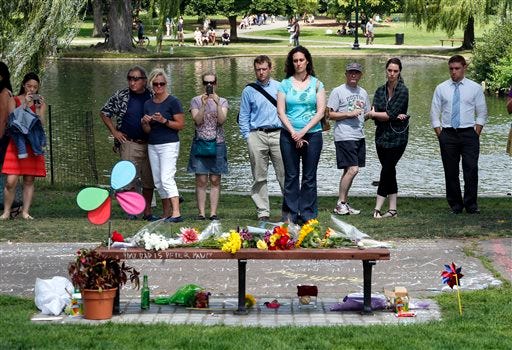 People pause by a bench at Boston's Public Garden Tuesday, where a small memorial has sprung up at the place where Robin Williams filmed a scene during the movie, "Good Will Hunting."