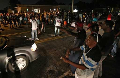 A group demonstrates Tuesday in the middle of Chambers Road outside the Greater St. Mark Missionary Baptist Church after a gathering with Michael Brown's family and Rev. Al Sharpton in Dellwood.