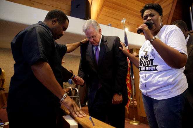 Missouri Gov. Jay Nixon, center, prays during a meeting in Florissant, Mo., of clergy and community members to discuss law enforcement's response to demonstrations over the killing of Michael Brown.