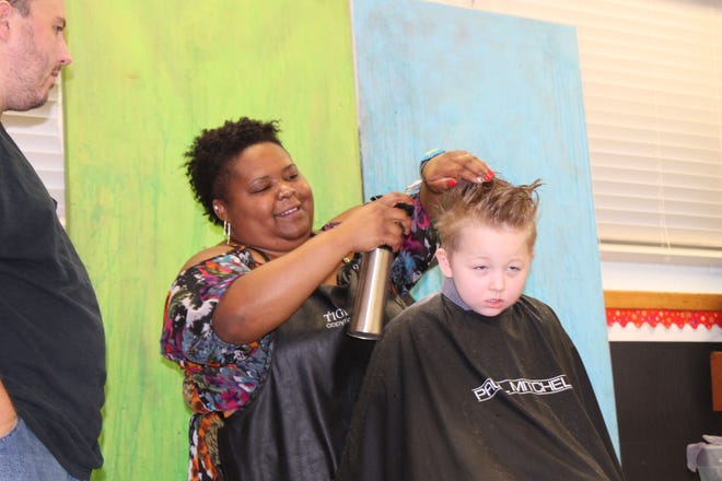 Danny Bright of Edgewater, left, watches as “Miss Kat” from New Smyrna Beach's Swanky Chic Salon gives his 5-year-old son Ashton Bright a back-to-school haircut during the orientation event.