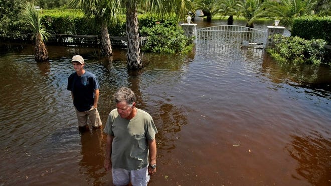 Jim Williams, right, with his son Weston Williams, in the Deer Run Equestrian Community in Loxahatchee in 2012 in the aftermath of Tropical Storm Isaac. (Gary Coronado/The Palm Beach Post)