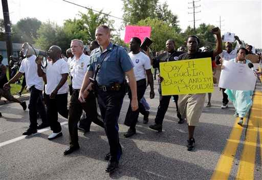Thousands of demonstrators peacefully march down a street Thursday with members of the St. Louis County Police and Missouri Highway Patrol in Ferguson, Mo. The Missouri Highway Patrol seized control of the St. Louis suburb Thursday, stripping local police of their law-enforcement authority after four days of clashes between officers in riot gear and furious crowds protesting the death of an unarmed black teen.