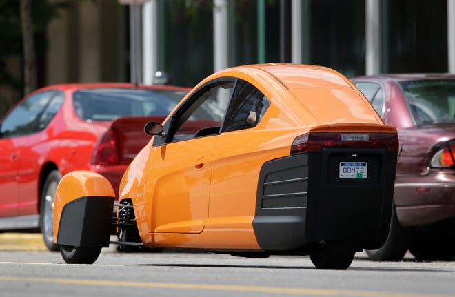 The Elio, a three-wheeled prototype vehicle, is shown in traffic in Royal Oak, Mich., Thursday, Aug. 14, 2014. Instead of spending $20,000 on a new car, Paul Elio is offering commuters a cheaper option to drive to work. His three-wheeled vehicle The Elio will sell for $6,800 car and can save on gas with fuel economy of 84 mpg.
