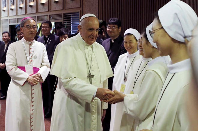 Pope Francis, second from left, shakes hands with a nun as he arrives to attend a meeting with the bishops of Korea at the headquarters of the Korean Episcopal Conference in Seoul, South Korea, Thursday, Aug. 14, 2014. Pope Francis called Thursday for renewed efforts to forge peace on the war-divided Korean Peninsula and for both sides to avoid "fruitless" criticisms and shows of force, opening a five-day visit to South Korea with a message of reconciliation as Seoul's rival, North Korea, fired five projectiles into the sea. (AP Photo/Korea Pool via Yonhap) KOREA OUT